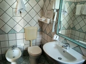 A bathroom with a toilet, bidet, sink, and mirror. - Tramonto D'oro Terme (Forio)
