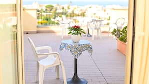 A balcony with a table and chairs, a potted plant, and a view of the sea. - Tramonto D'oro Terme (Forio)