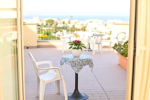 A balcony with a table and chairs, a potted plant, and a view of the sea. - Tramonto D'oro Terme (Forio)