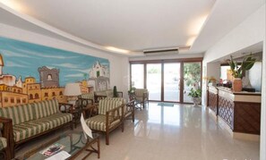A hotel lobby with a large mural, a reception desk, and seating area. - Tramonto D'oro Terme (Forio)