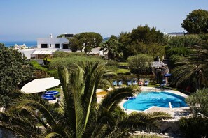 A pool area with palm trees, lounge chairs, and a view of the sea. - Ideal (Forio)