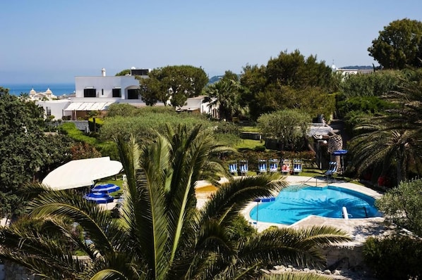 A pool area with palm trees, lounge chairs, and a view of the sea. - Ideal (Forio)