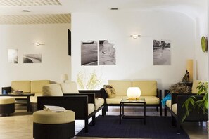 A modern living room with a sofa, armchairs, a coffee table, and wall-mounted artwork. - Ideal (Forio)
