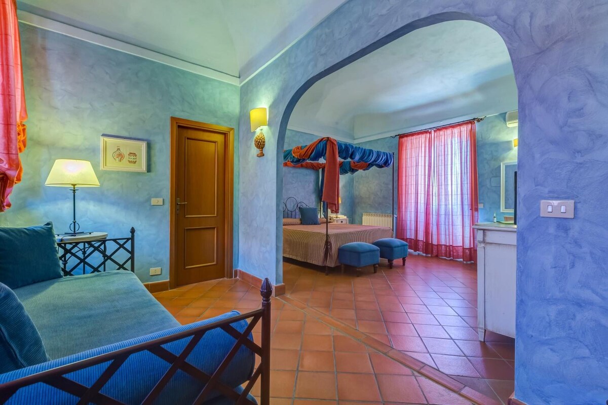 Un dormitorio con cama, escritorio, silla, ventana con cortinas y baño con cortina de ducha.