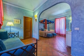 A bedroom with a bed, a desk, a chair, a window with curtains, and a bathroom with a shower curtain. - Casa Delle Monache Boutique Resort (Castiglione di Sicilia)