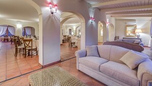 A spacious hotel lobby with a dining area, a sofa, and a large mirror. - Casa Delle Monache Boutique Resort (Castiglione di Sicilia)