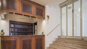 A wooden reception desk with bookshelves, a staircase, and a glass door. - Hotel Orizzonte (Letojanni)