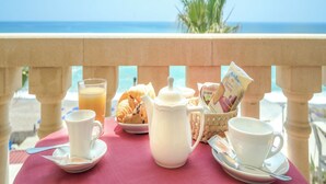 A table with breakfast items, a pitcher, and a cup, set against a balcony with a view of the sea. - Hotel Orizzonte (Letojanni)