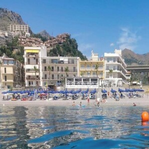 A coastal hotel with multiple floors, a beach area with umbrellas, and a clear view of the sea. - Hotel Orizzonte (Letojanni)