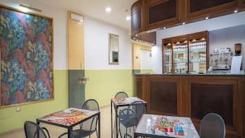 Un coin repas avec une table et des chaises, un grand tableau accroché au mur et des placards en bois au-dessus du comptoir.