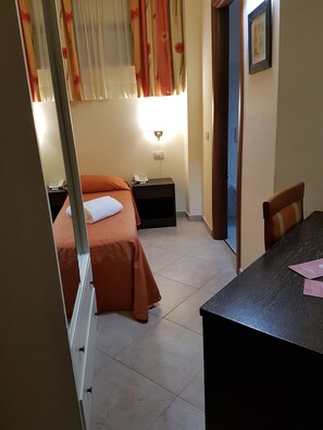 A hotel room with two beds, a bedside table with a phone, a desk with papers, and a wall-mounted light. - Hotel Orizzonte (Letojanni)