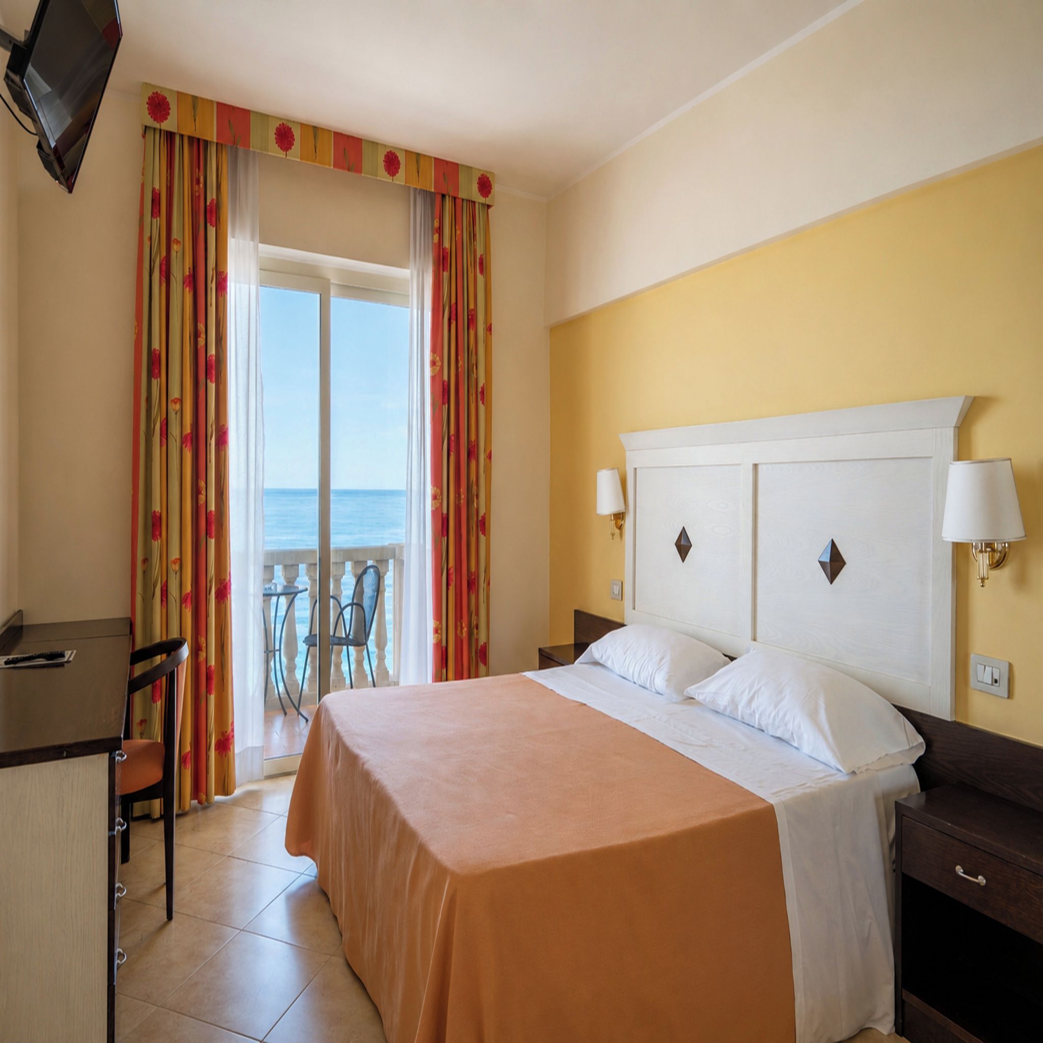 Una habitación de hotel con una cama, lámparas de noche, un escritorio y una silla.