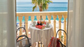 A balcony with a table set for two, overlooking a palm tree and the sea. - Hotel Orizzonte (Letojanni)