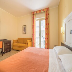 A hotel room with a bed, a sofa, a desk, and a balcony with curtains. - Hotel Orizzonte (Letojanni)