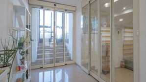 A modern hotel lobby with a staircase, glass doors, and a plant display. - Hotel Orizzonte (Letojanni)