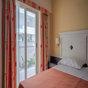 A hotel room with a bed, a nightstand, a lamp, and a view of the outside. - Hotel Orizzonte (Letojanni)