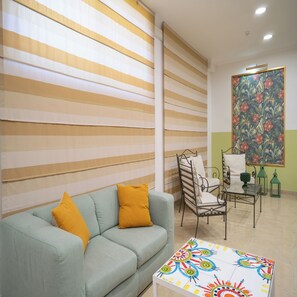 A living room with a sofa, a coffee table, a metal chair, and a painting on the wall. - Hotel Orizzonte (Letojanni)