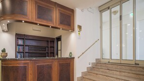 A wooden reception desk with bookshelves, a staircase, and a glass door. - Hotel Orizzonte (Letojanni)