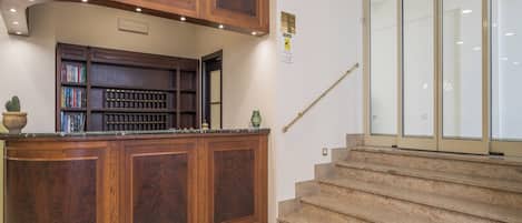 Un mostrador de recepción de madera con estanterías, una escalera y una puerta de cristal.
