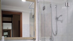 Ein Badezimmer mit Duschkabine aus Glas, einem Waschbecken mit Spiegel darüber und einem Handtuchhalter.