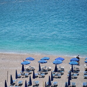 Una playa con filas de tumbonas y sombrillas azules.