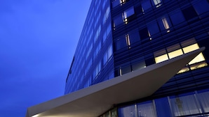 A modern building with a glass facade and a white overhang structure. - UNA Hotels San Vitale Bologna (Bologna)