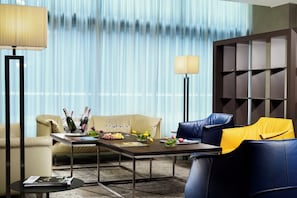 A modern hotel room with a dining table set for a meal, a sofa, a chair, and a lamp. - UNA Hotels San Vitale Bologna (Bologna)