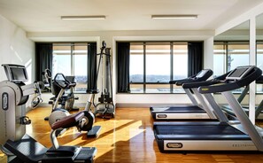 Un gimnasio moderno con máquinas de cardio, una máquina de remo y un muro de espejos.