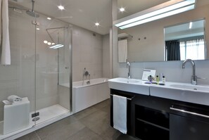 Un baño moderno con ducha envuelta en vidrio, una bañera independiente y un tocador con un espejo grande.