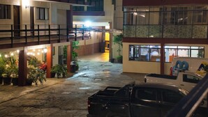 A courtyard with a parking area, buildings with multiple floors, and a van parked on the right. - Hotel Mesón del Bosque  (Querétaro)