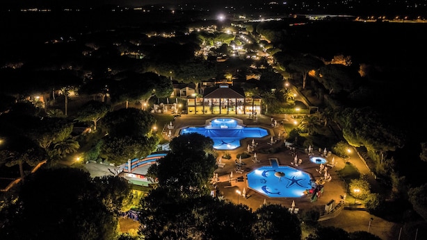 Un complejo turístico con varias piscinas, un edificio grande con cúpula y zonas ajardinadas aledañas.