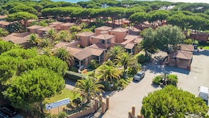 Vista aérea de una zona residencial con varias casas, un estacionamiento y un letrero que indica 'Argentario International Village'.