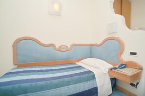 A bedroom with a bed, a bedside table, and a wall-mounted light fixture. - Albergo Italia (Casamicciola Terme)
