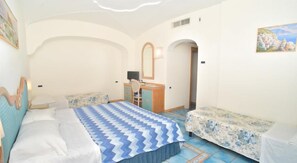 A bedroom with a bed, two bedside tables, a desk with a chair, and a door leading to another room. - Albergo Italia (Casamicciola Terme)