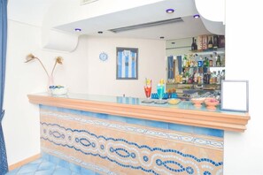 A bar area with a tiled counter, a framed jersey, and a variety of bottles and glasses. - Albergo Italia (Casamicciola Terme)