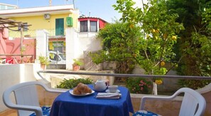 A balcony with a table set for two, featuring a plate of food, a teapot, and cups. - Albergo Italia (Casamicciola Terme)