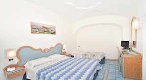 Un dormitorio con cama, mesita de noche y un escritorio con ordenador.