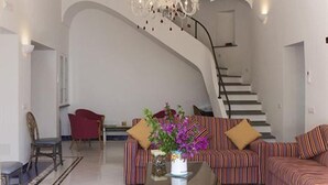 Ein modernes Wohnzimmer mit einer geschwungenen Treppe, einer Chandelüster und einem Sofa mit gestreiften Kissen.