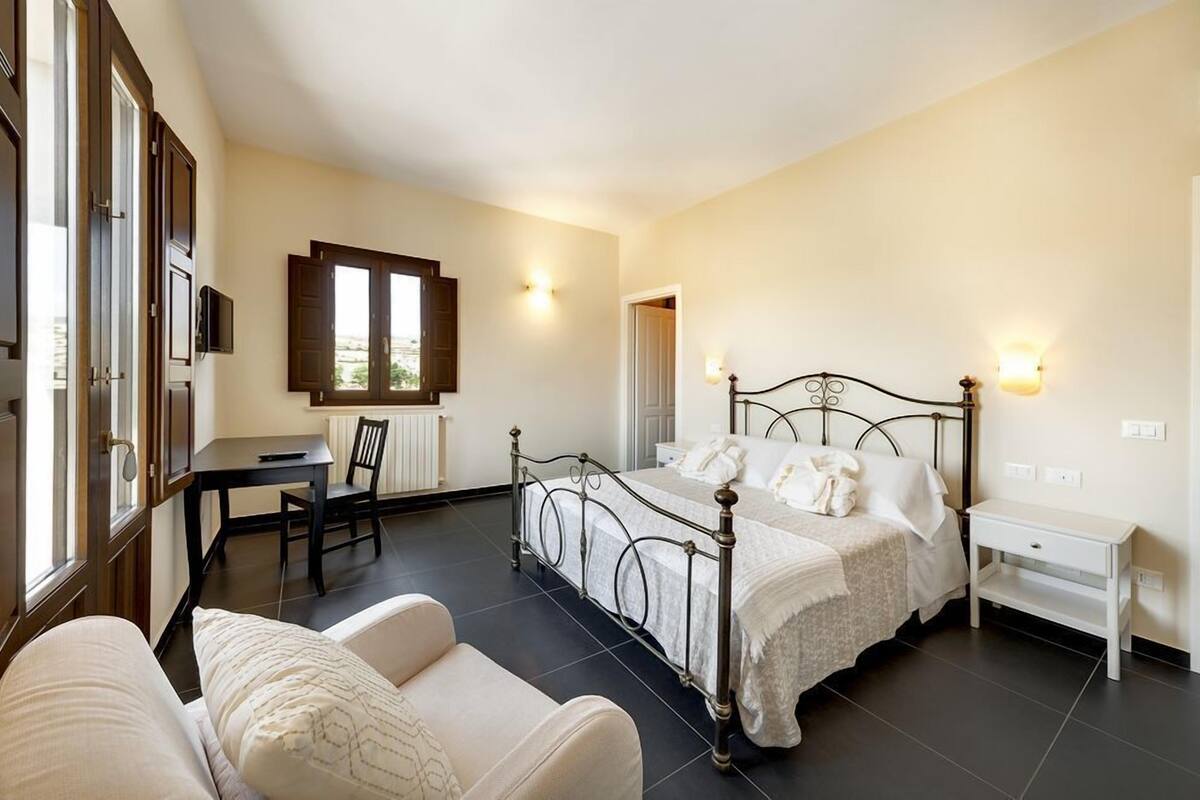 A bedroom with a bed, bedside table, and a desk with chair.