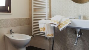 A bathroom with a bidet, a towel rack with towels, a sink, and a mirror. - Arucimeli Resort (Ragusa)