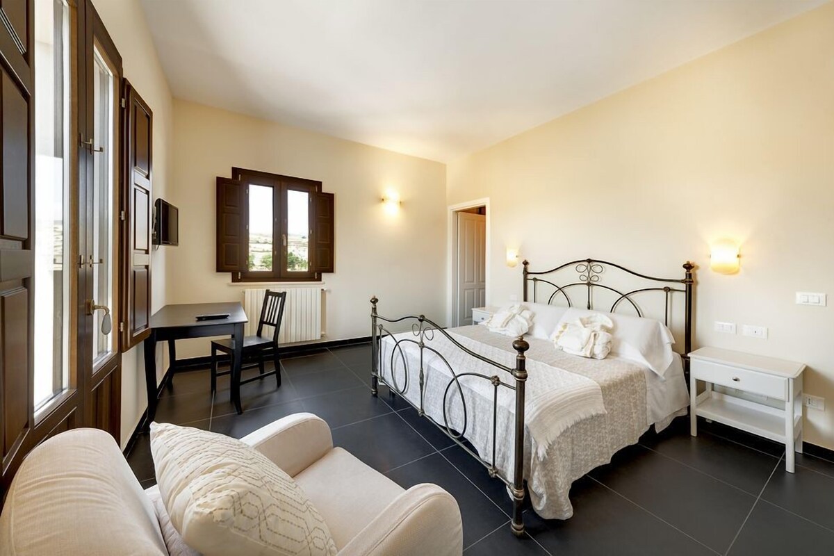 A bedroom with a bed, bedside table, and a desk with chair.