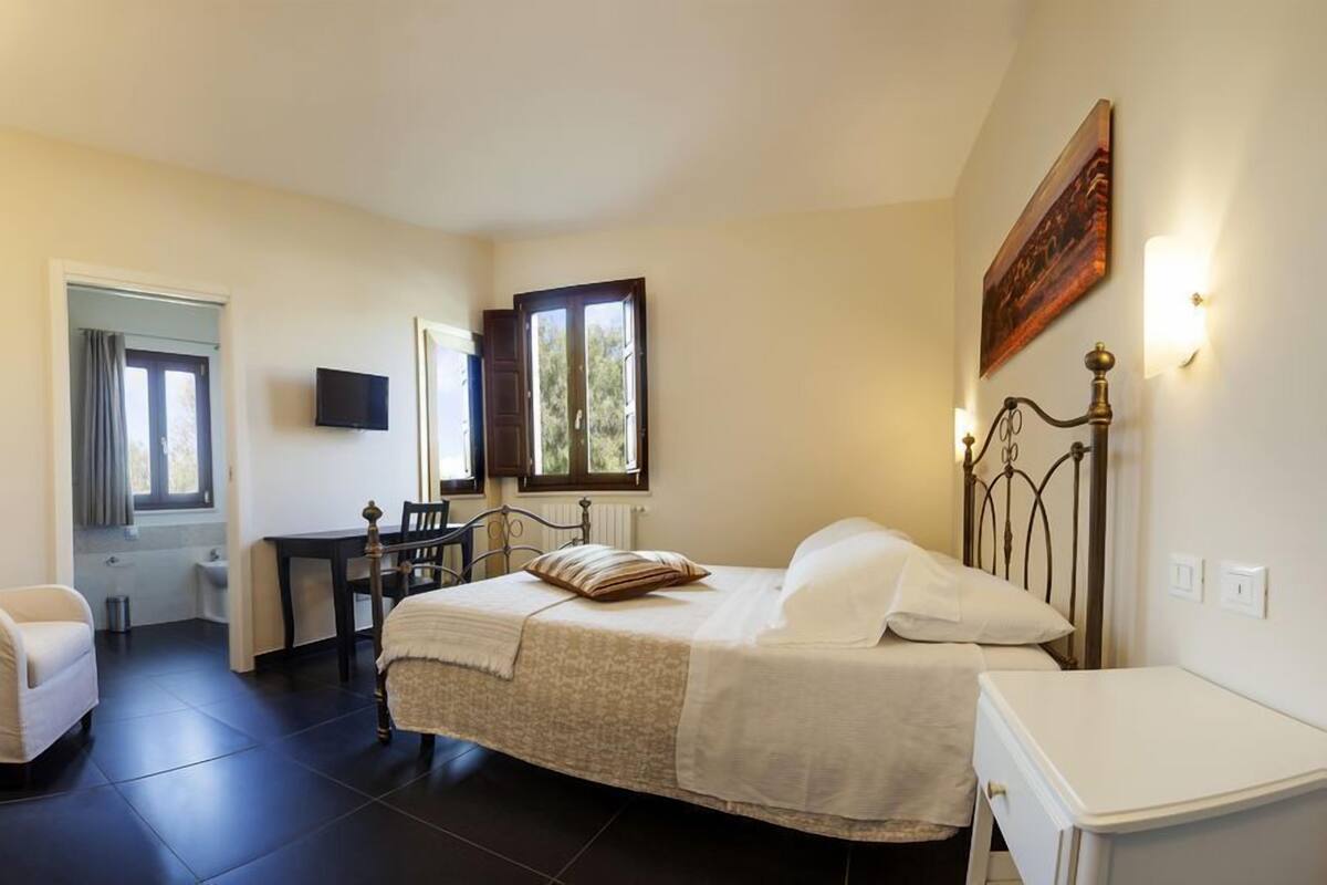 A bedroom with a bed, a desk, a chair, and a TV.