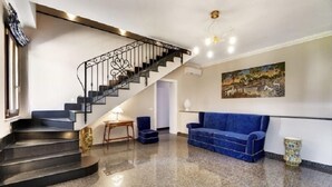 A modern interior with a staircase, a blue sofa, and a painting on the wall. - Arucimeli Resort (Ragusa)