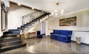 A modern interior with a staircase, a blue sofa, and a painting on the wall. - Arucimeli Resort (Ragusa)