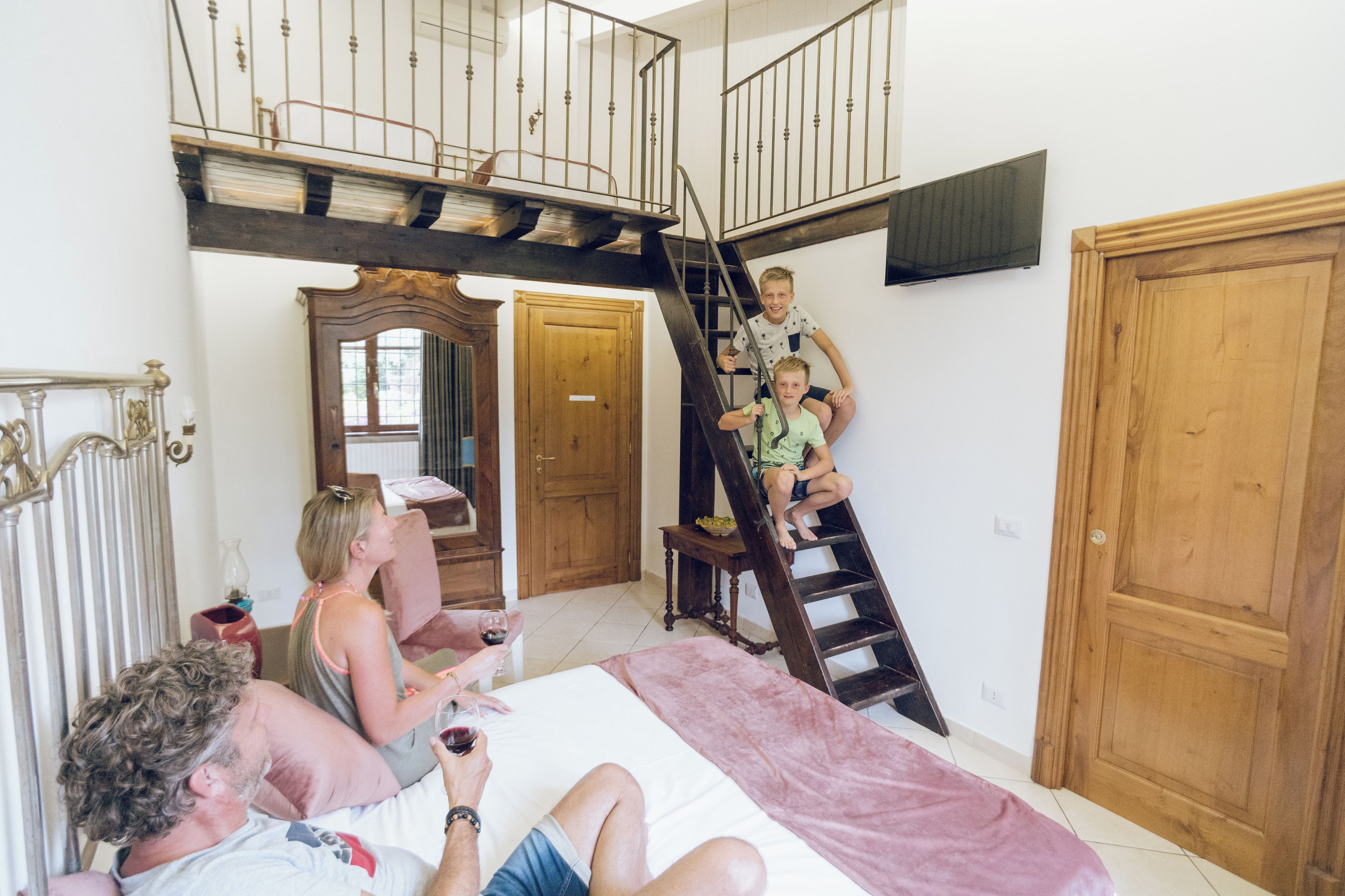 Ein Schlafzimmer mit Bett, einer Holztür, einer Treppe und einem Spiegel.