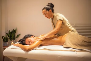 Eine Massageanwendung in einem Spa-Ambiente mit Massageliege, Klient und Therapeut.