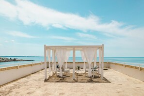 Un espace extérieur aménagé avec des sièges blancs, offrant une vue sur la mer.