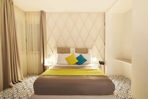 Une chambre d’hôtel avec un lit, une table de chevet, une lampe et une fenêtre avec des rideaux.