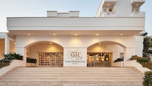Une grande entrée d'hôtel, avec une enseigne bien visible, un escalier menant à l'étage et une architecture moderne.