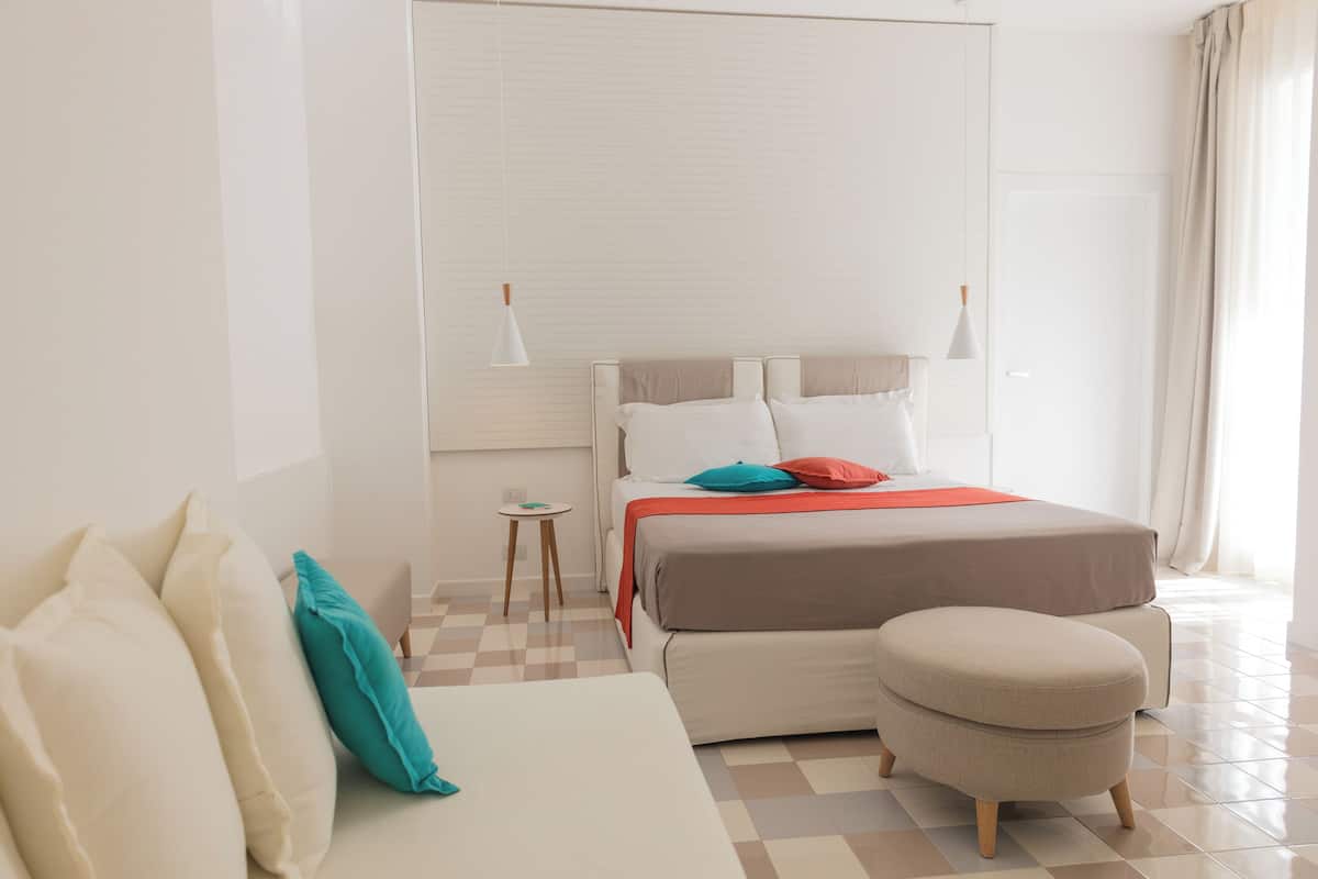 Ein modernes Hotelzimmer mit einem großen Bett, einer Couch und einem kleinen Tisch.